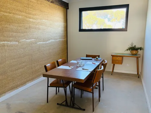 Small break-out meeting room with rammed-earth wall and timber table