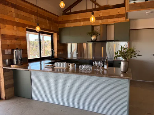 Kitchen island with copper pendants, stainless splashback and views across the paddocks