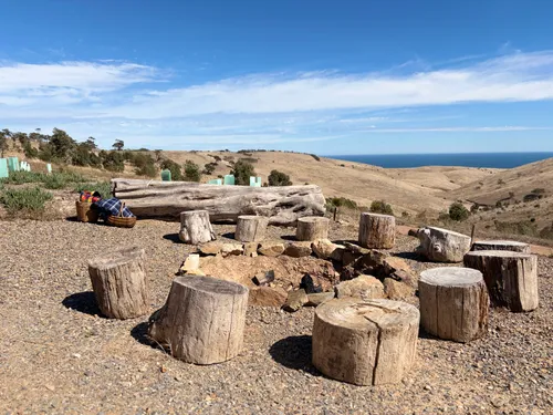 Outdoor fire pit with log stump seating and ocean views