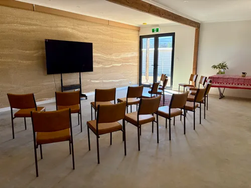 Main lecture room with chairs arranged in a semicircle facing a large screen